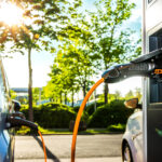 Elektroautos an Ladestation auf Firmengelände im Gegenlicht – Electric Car at Charging Station