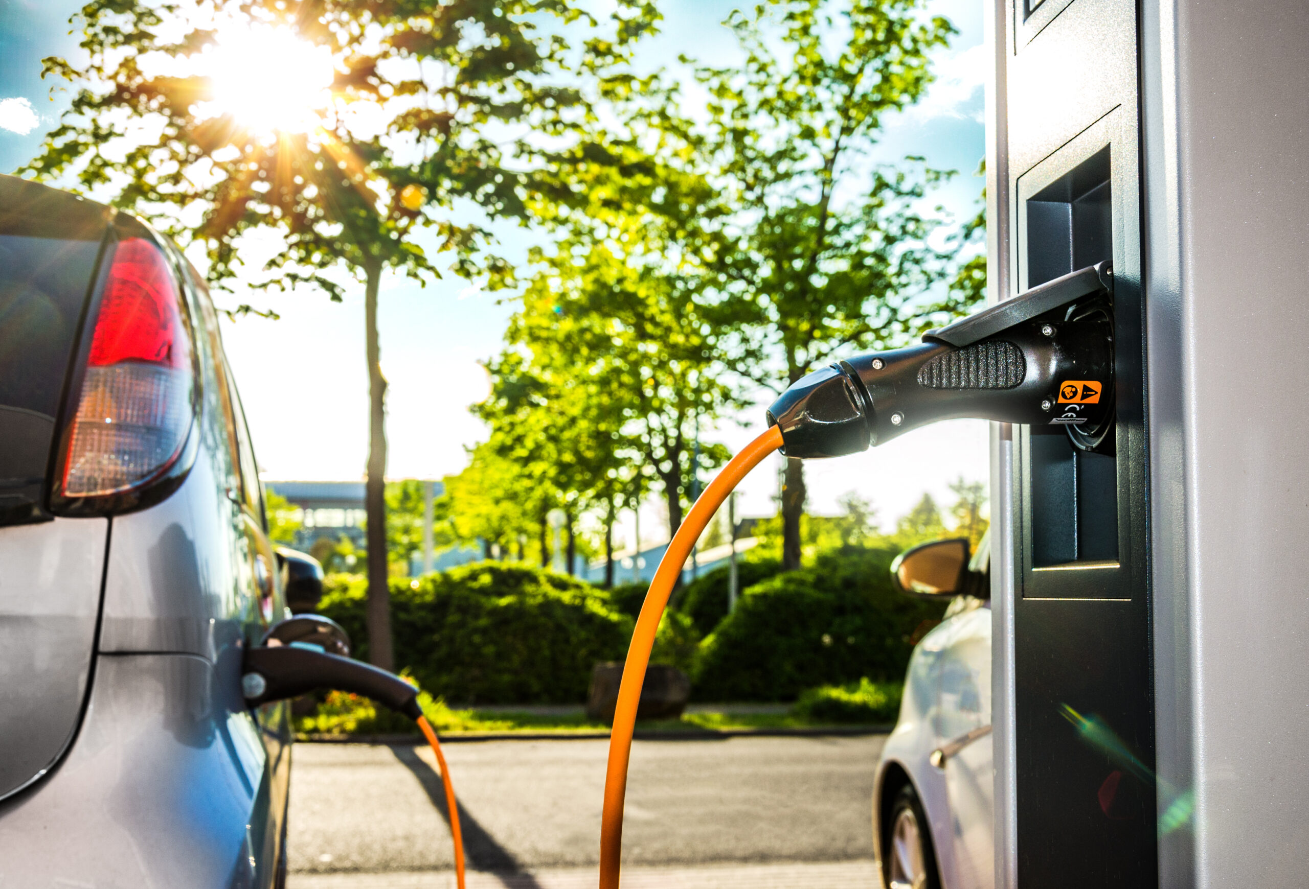 Elektroautos an Ladestation auf Firmengelände im Gegenlicht – Electric Car at Charging Station